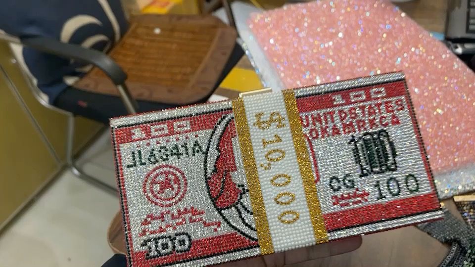 rhinestone crystal mesh clutch shaped like a stack of banknotes, held in hand